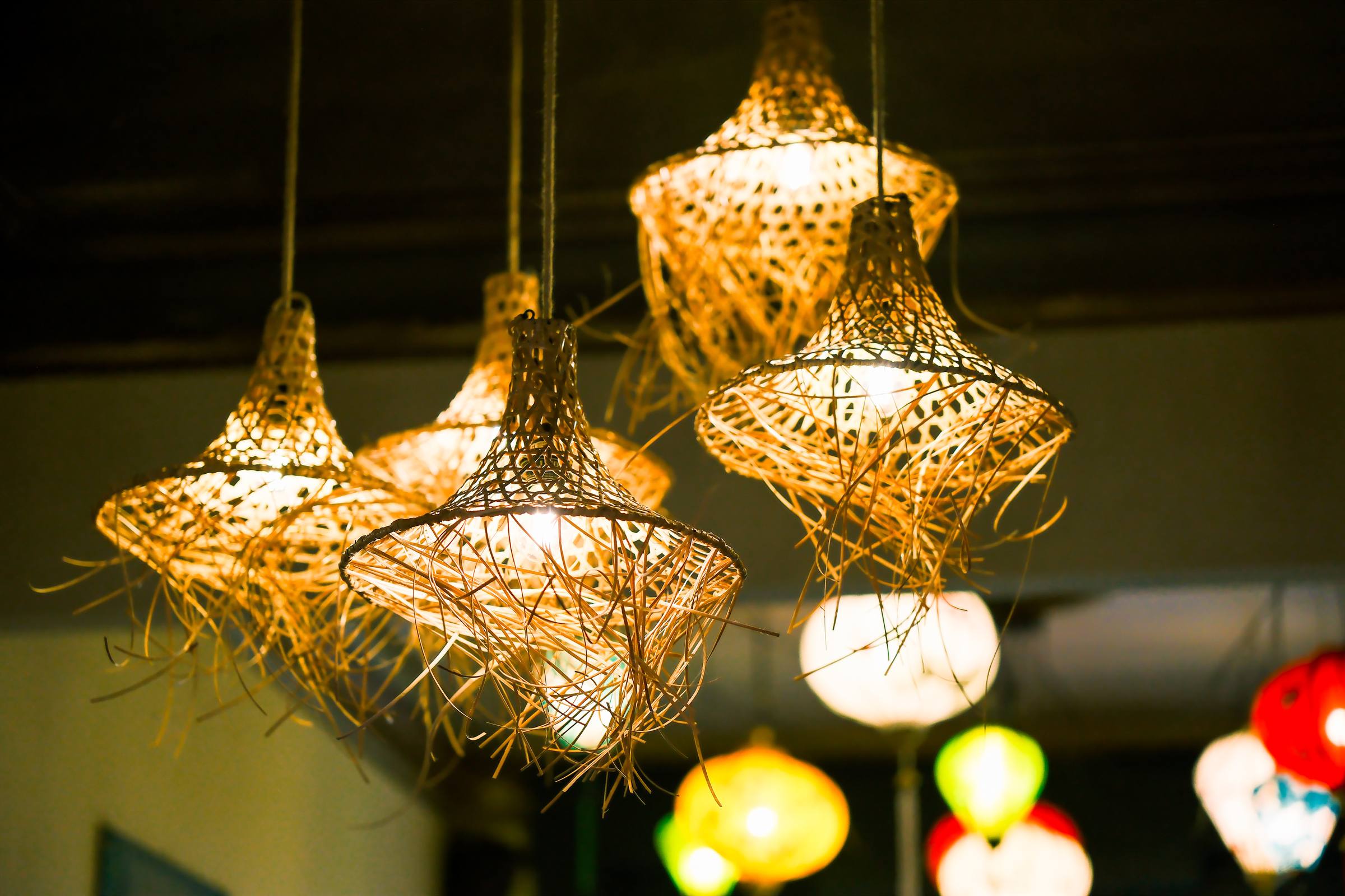Woven rattan lamps glowing above the tables